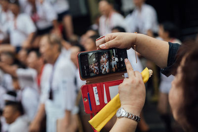 Midsection of woman photographing using mobile phone