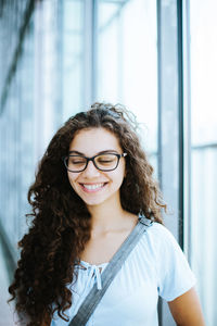 Close-up of beautiful smiling woman against window