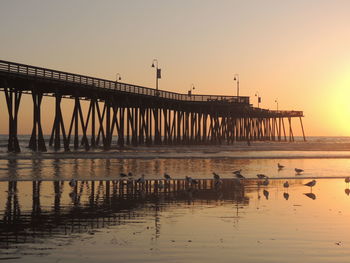 Silhouette bridge over sea against clear sky during sunset