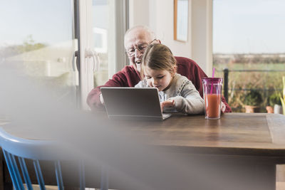 Grandfather and granddaughter using laptop together