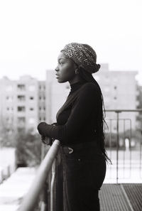 Young woman standing in balcony against buildings