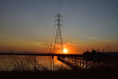 Silhouette electricity pylon against sky during sunset