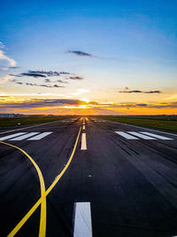 Airplane runway  by sea against sky during sunset