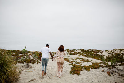 Mixed race couple holding hands walking on beach