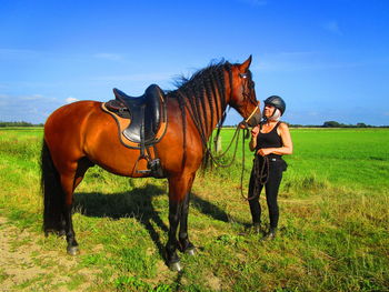 Woman with horse standing on field