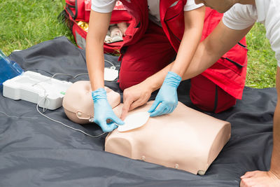 Man instructing while paramedic practicing cpr on dummy