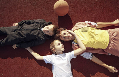 Laid-back laughter, unwinding with children on the basketball court surface with mother