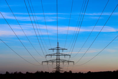 Low angle view of silhouette electricity pylon against sky