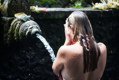 Rear view of woman praying in fountain