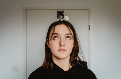 Portrait of young woman against wall at home