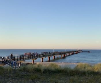 Pier over sea against clear sky during sunset