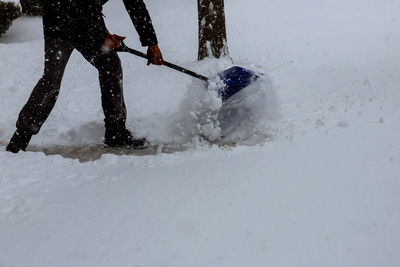 Low section of man cleaning snow on footpath