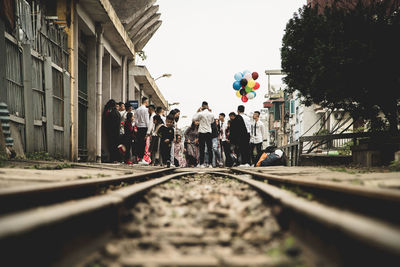 People walking on railroad track in city