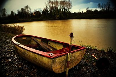 Boat moored at lakeshore against sky