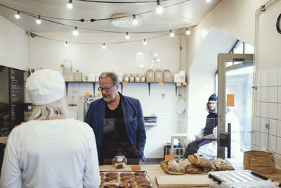 Male customer buying food from owner at bakery