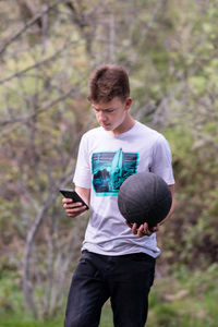 Full length of teenage boy using mobile phone