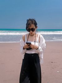 Young woman using mobile phone at beach