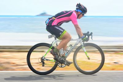 Side view of man riding bicycle against sea