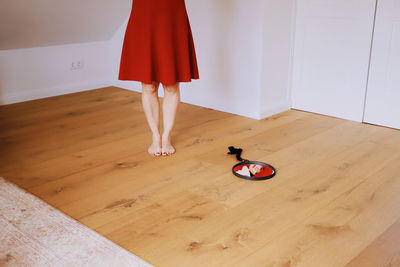 Low section of woman standing by mirror on hardwood floor