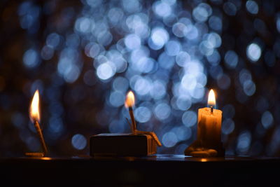 Illuminated candles against defocused lights