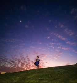 Boy in sports clothing on hill at sunset