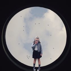 Digital composite image of surprised girl covering mouth standing on sky light against sky