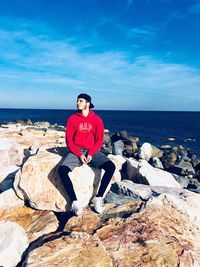 Portrait of man on rock by sea against sky