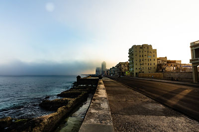 Sea by buildings against sky in city