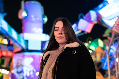 Young woman looking away while standing at night