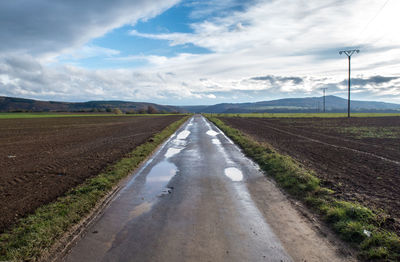 Road amidst field against sky