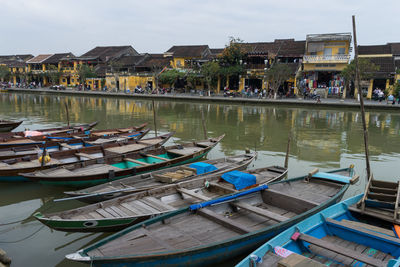 Boats moored at harbor by buildings in city against sky