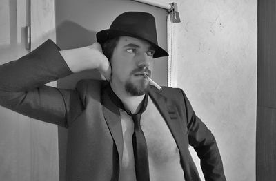 Portrait of young man looking away against wall