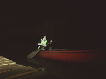 Man standing by boat at night