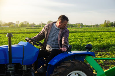 A farmer drives a tractor while harvesting potatoes. first potato harvest in early spring. agro