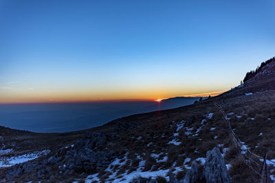 Scenic view of snowcapped mountains against clear sky during sunset