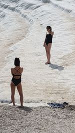 Full length rear view of two women walking on beach