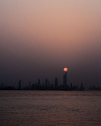 Silhouette of buildings in city at sunset