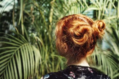 Rear view of woman with hair buns against palm tree