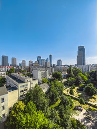 Trees and modern buildings against clear blue sky