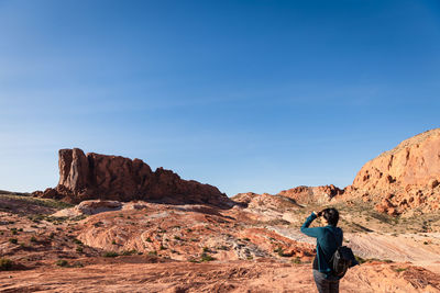 Rear view of man on rock against sky