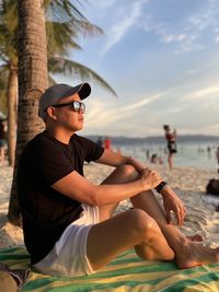 Side view of man sitting at beach