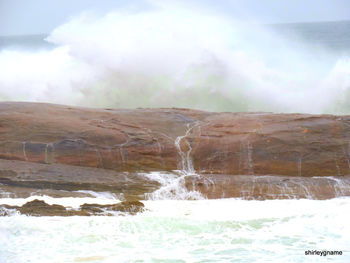 Scenic view of sea by mountain against sky