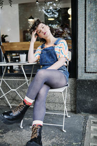 Beautiful woman with head in hand sitting on chair at sidewalk cafe