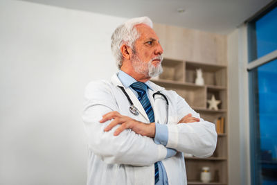 Portrait of doctor standing against wall