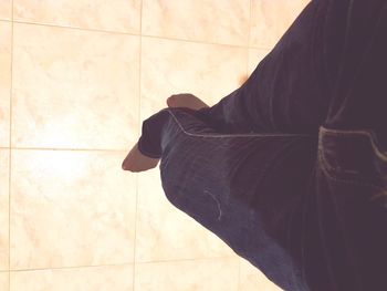 Low section of man standing on tiled floor