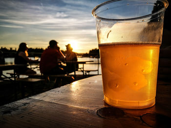 Beer glass on table against sky during sunset