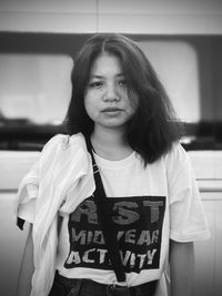 Portrait of young woman standing against wall