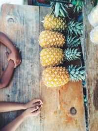 Pineapples and hands of two children on wooden table
