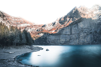 Scenic view of lake by snowcapped mountains against sky