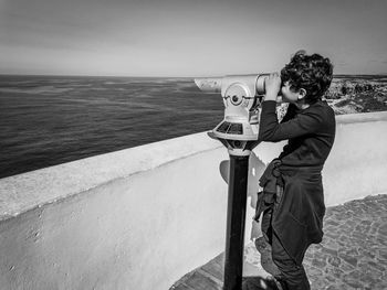 Man photographing while standing by sea against sky